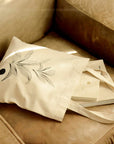 canvas eco bag with the illustration of leaves placing on the sofa with books