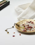 citrine crystal divination pendulum on the metal plate with white stones and dried rose petals