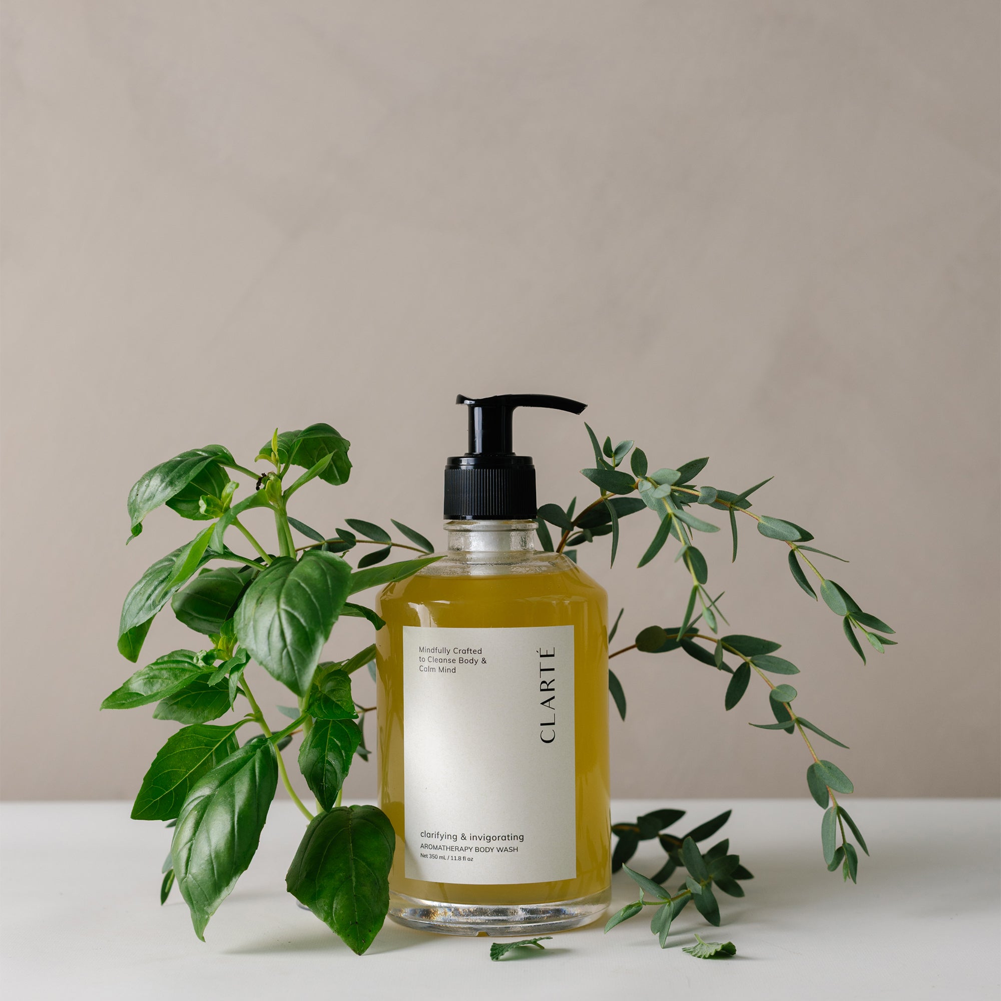 organic aromatherapy body wash in pump bottle surrounded by fresh green botanicals, highlighting clean formulation.