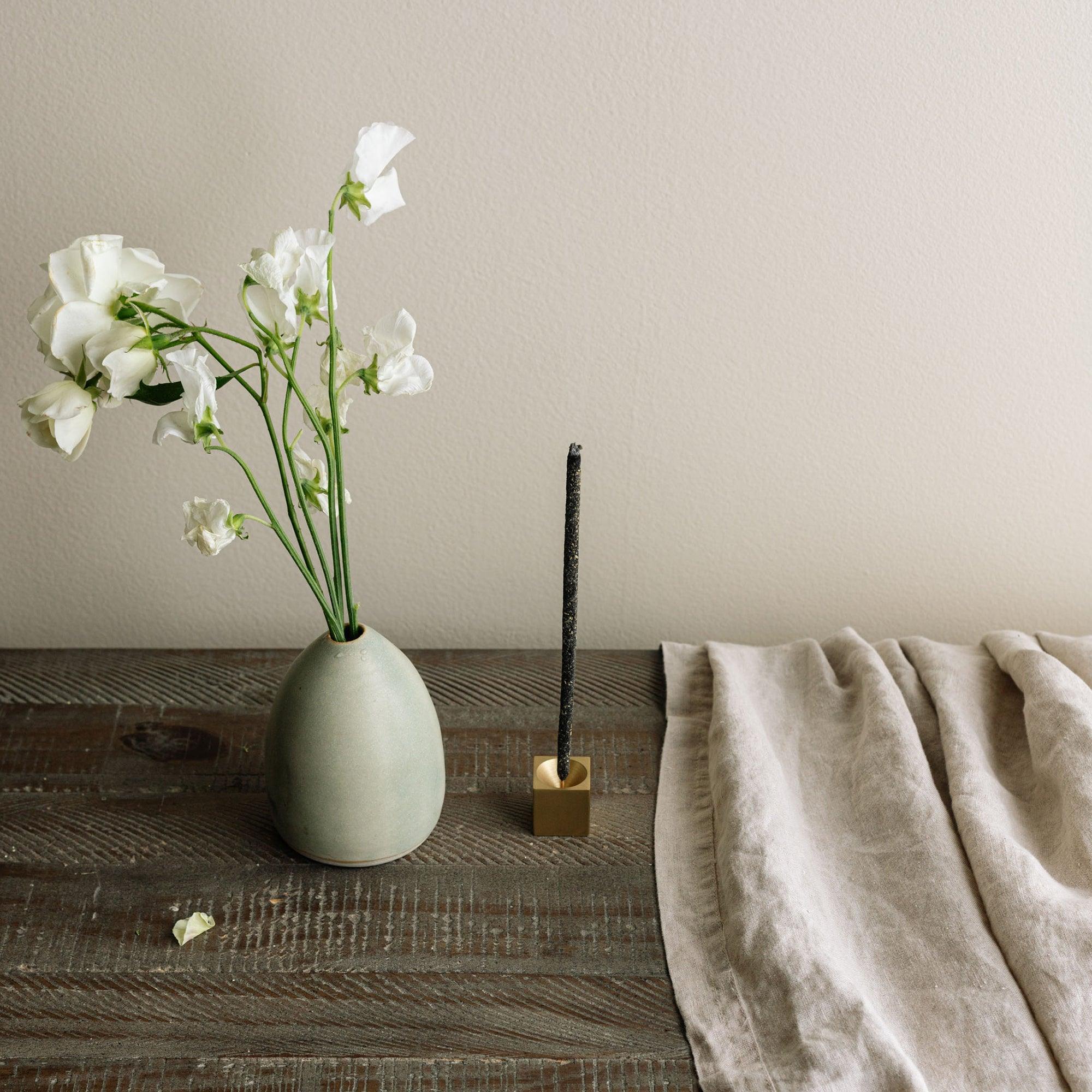 flowers with a vase, incense stick with incense holder, linen cloth on the wooden table