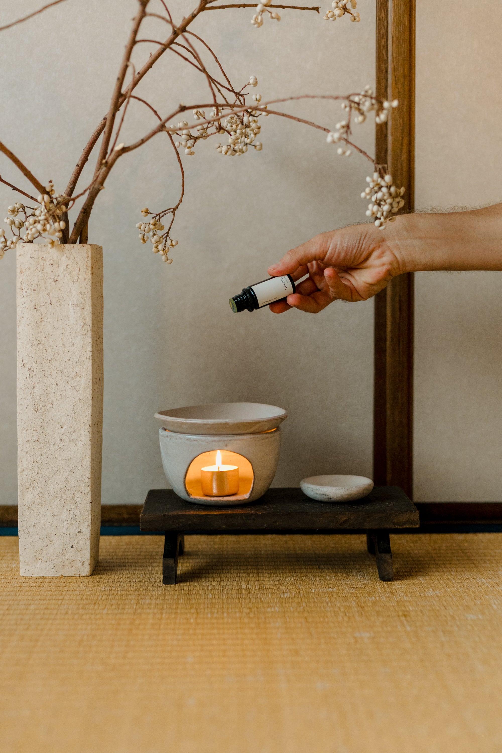 Ethically sourced Palo Santo essential oil being dropped onto an aromatherapy burner, creating a calming and purifying ritual by Cedar and Myrrh