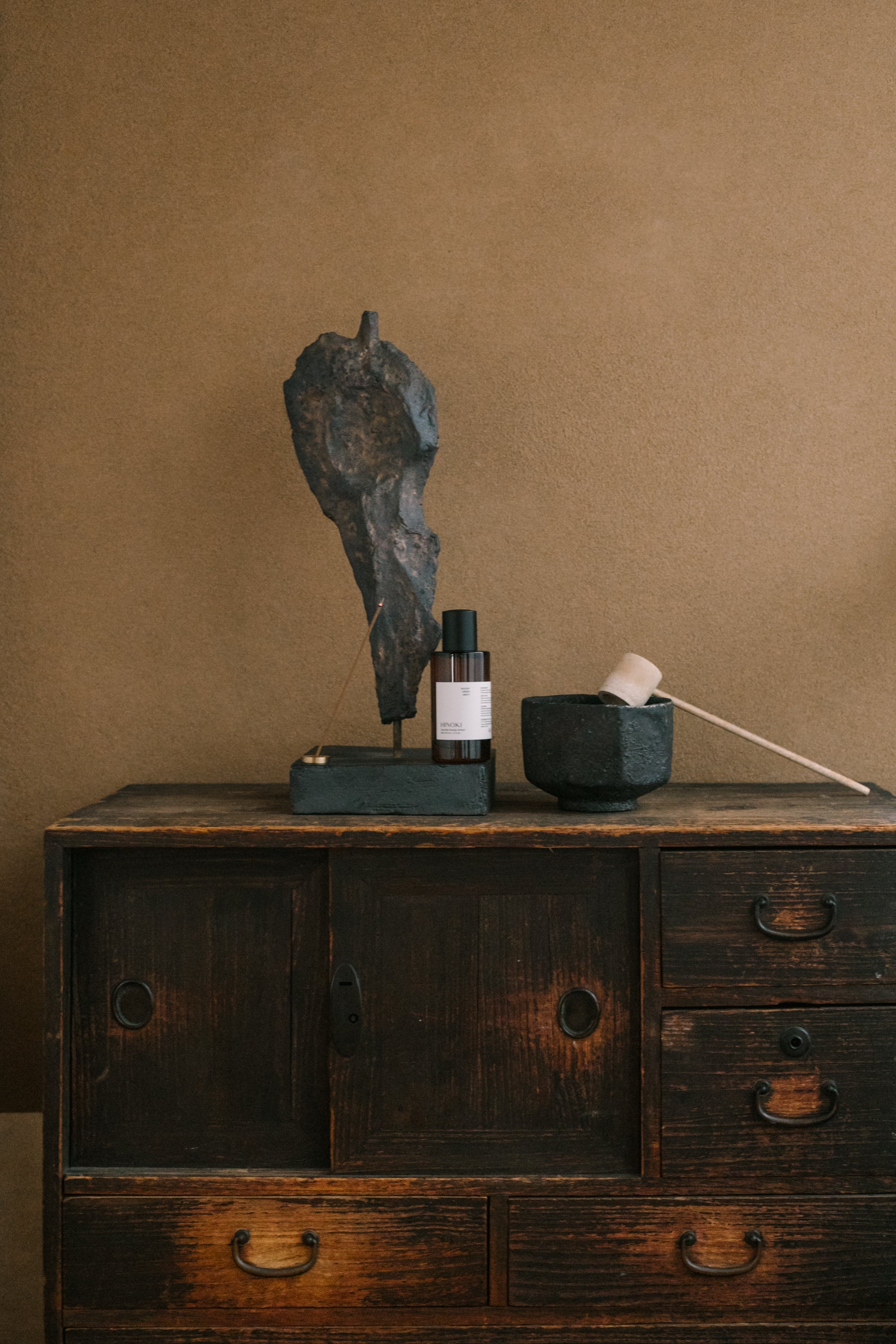 Fraîcheur Aromatherapy Room Spray placed beside a brass incense holder and black ceramic bowl on a rustic wooden cabinet, creating an energizing and balanced ritual mood.