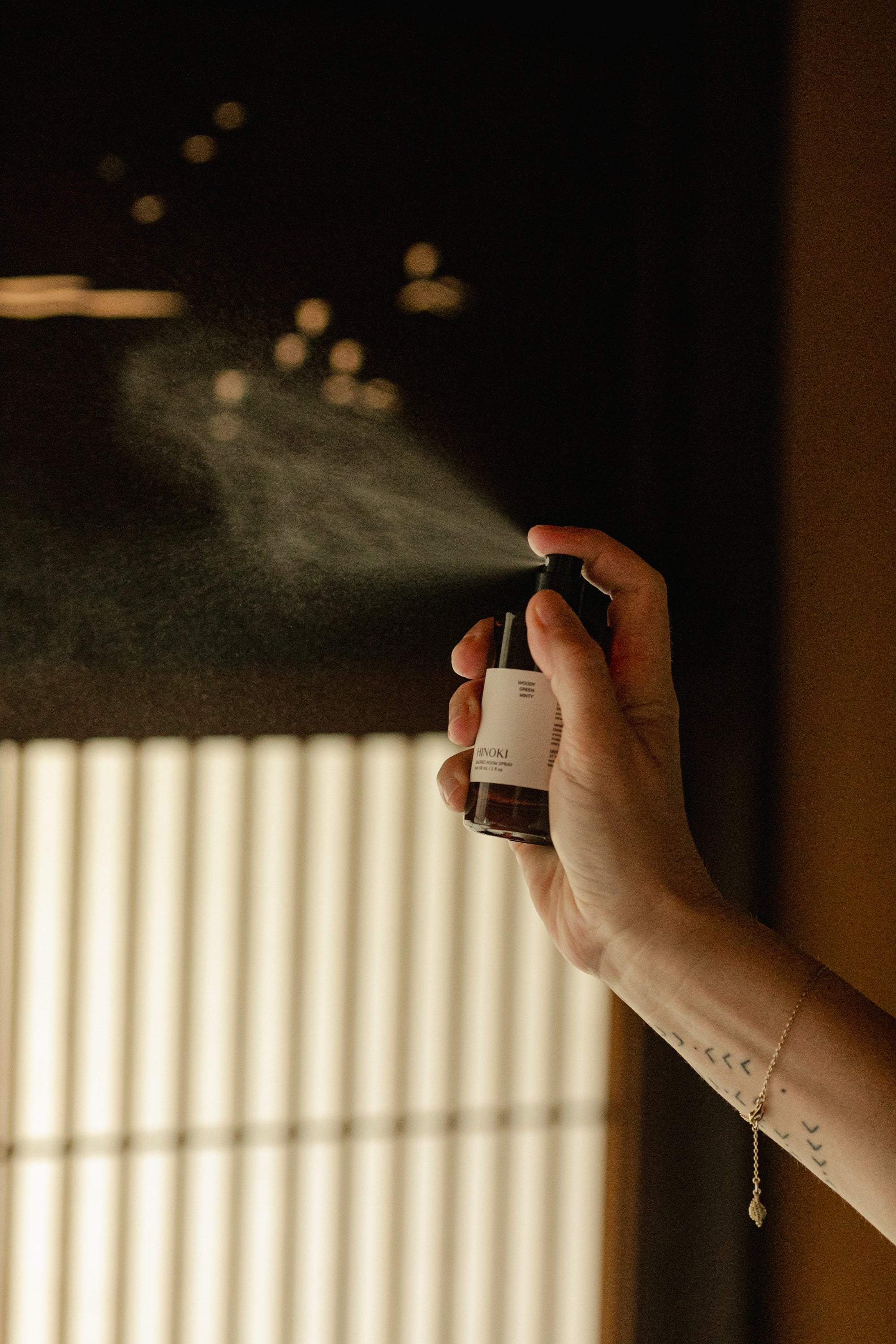 A hand spraying Fraîcheur Aromatherapy Room Spray into the air, releasing a refreshing herbal-citrus mist that awakens the senses and revitalizes the atmosphere.