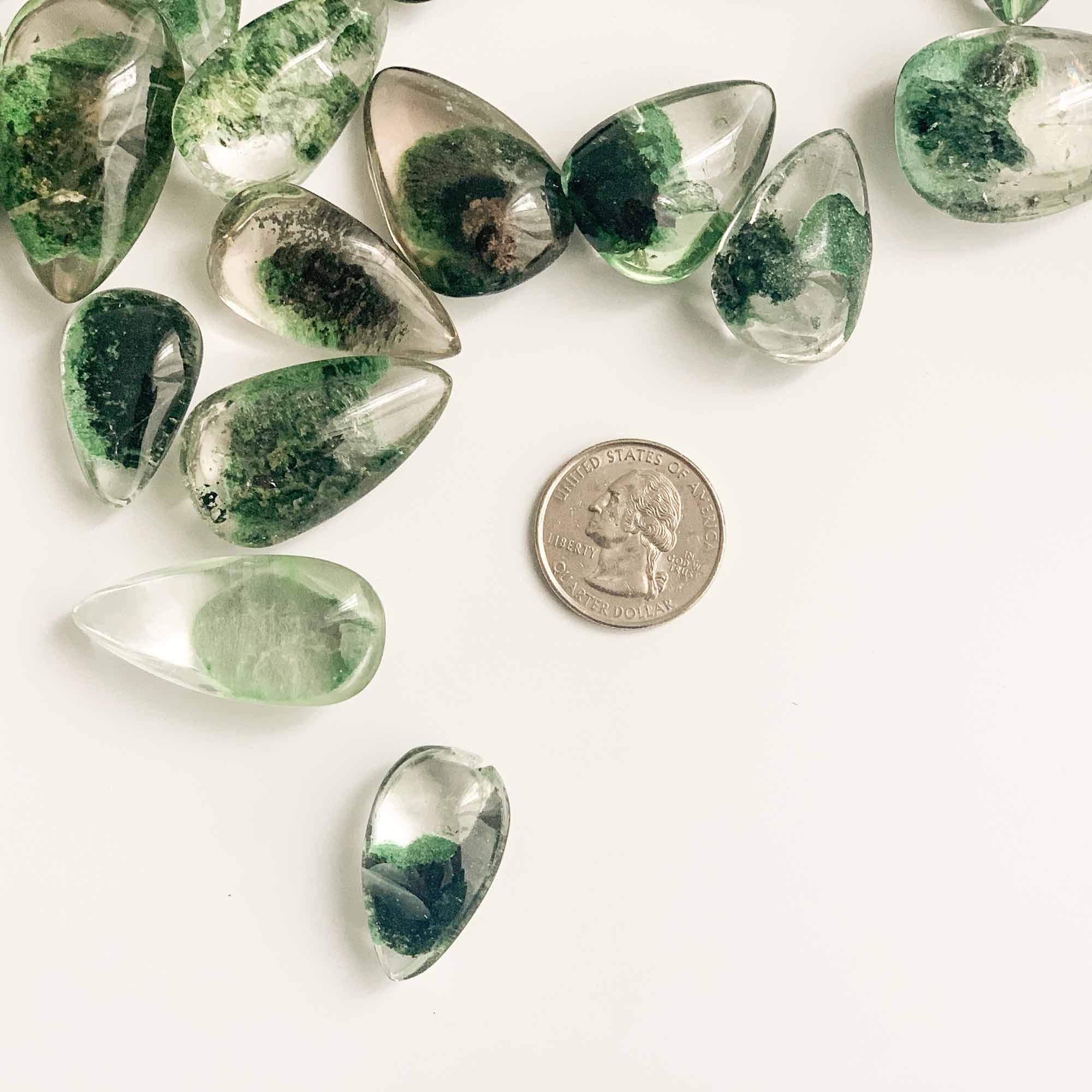 quarter dollar coin and several pieces of green ghost crystals with different size and pattern