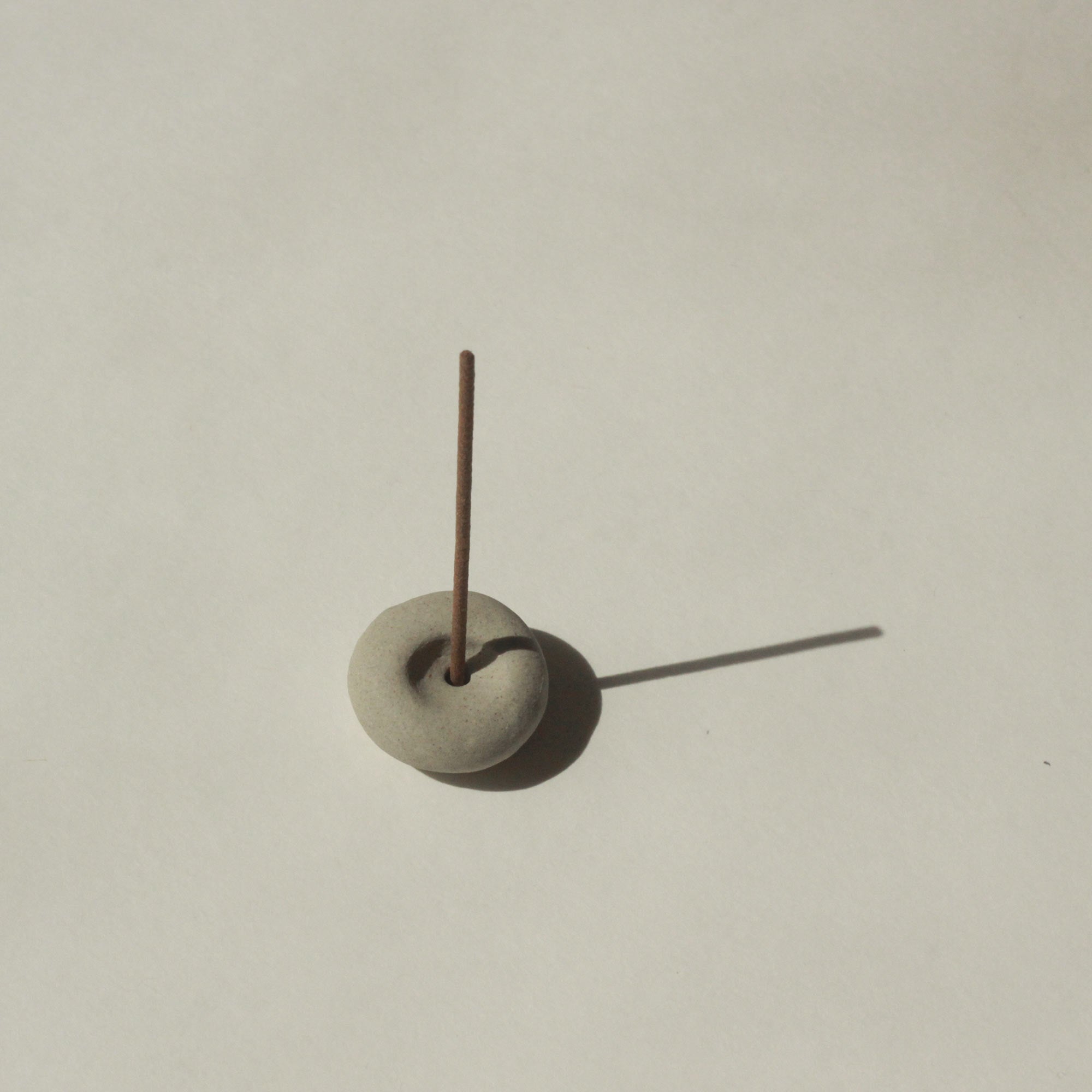 mini grey ceramic pebble incense holder with incense stick