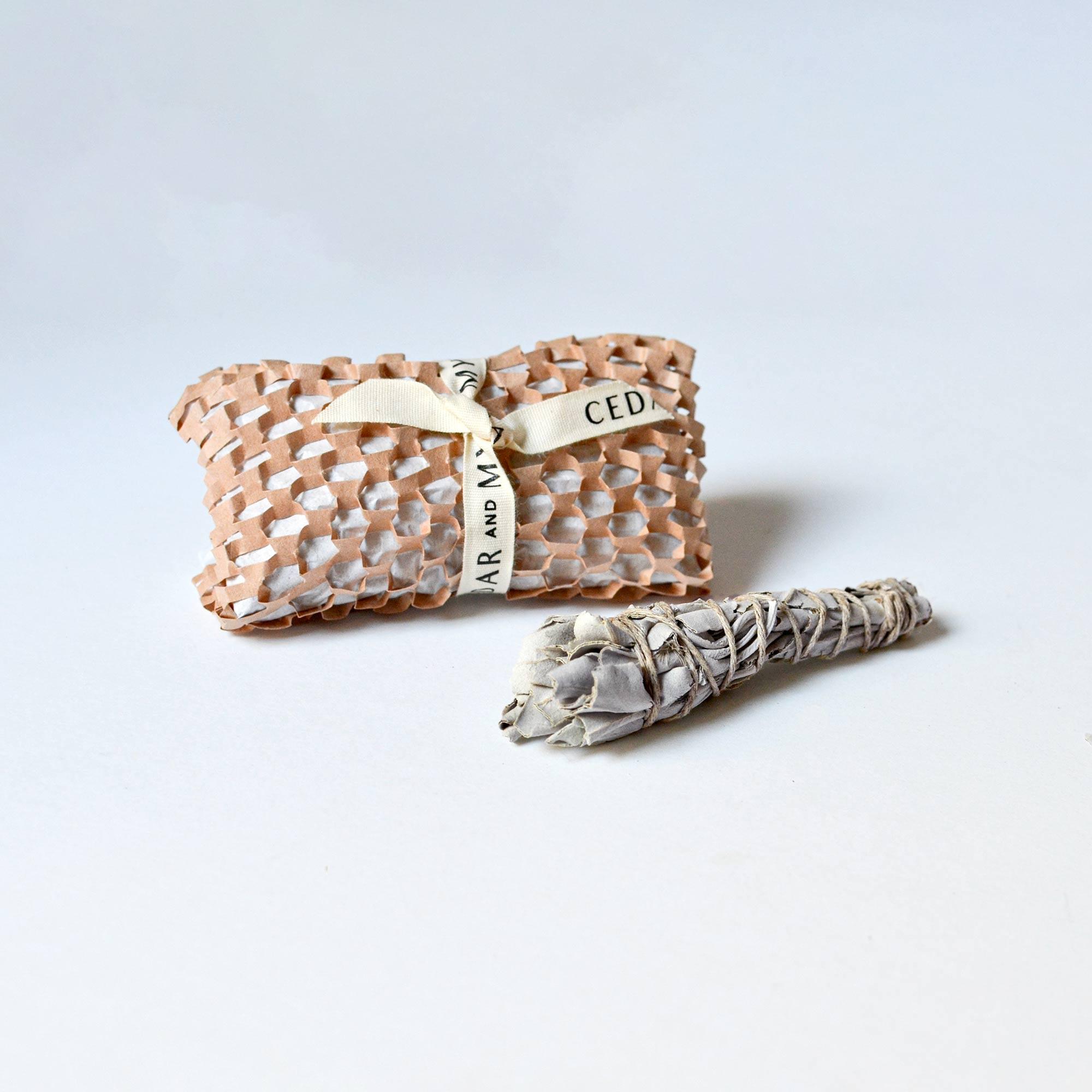 Mini white sage smudge stick and wrapped package with ribbon at the back.