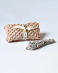Mini white sage smudge stick and wrapped package with ribbon at the back.