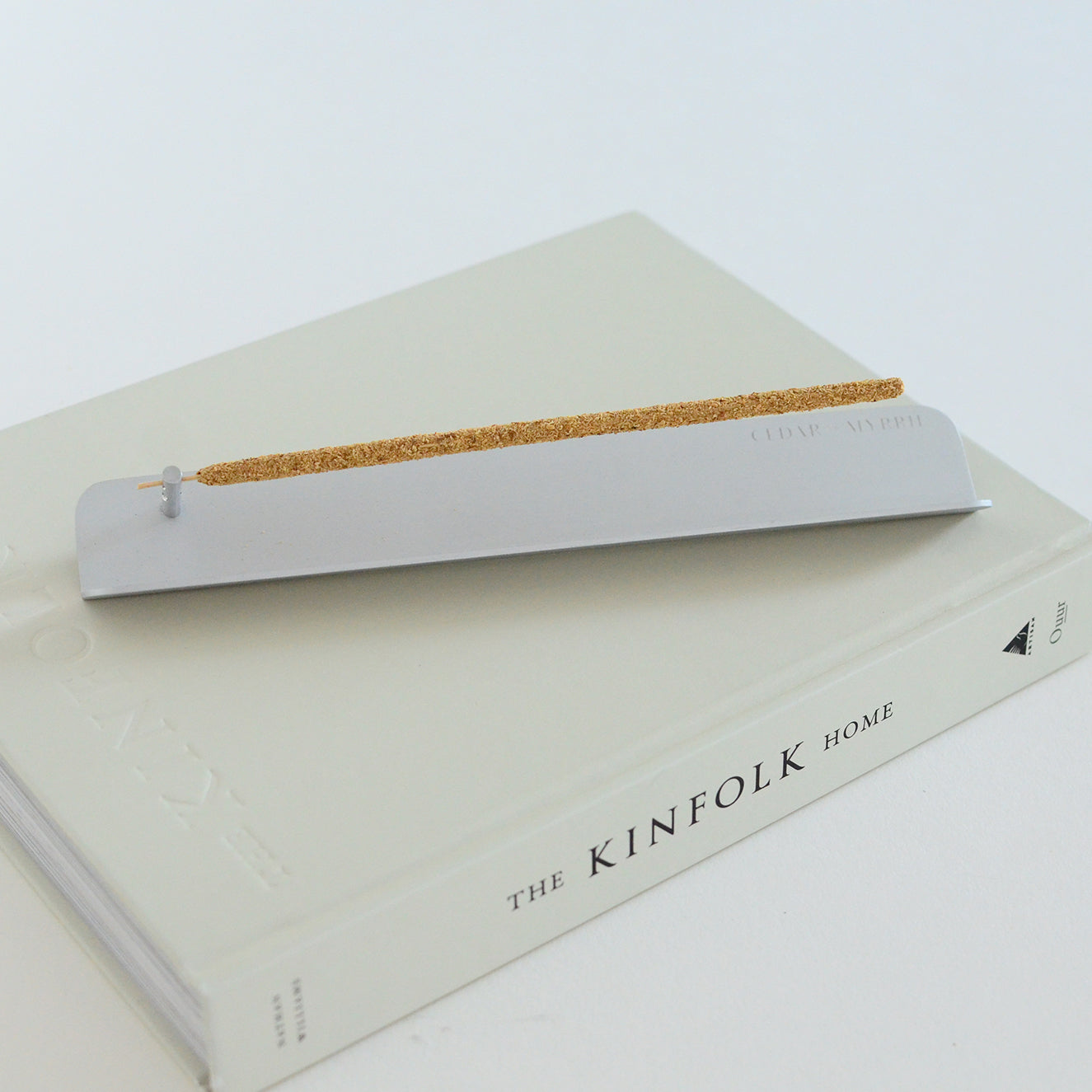 Minimal aluminum incense holder burning stick incense on book in modern home setting