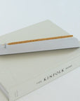 Minimal aluminum incense holder burning stick incense on book in modern home setting