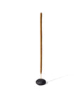 a raw black clay pebble shaped incense holder with incense stick
