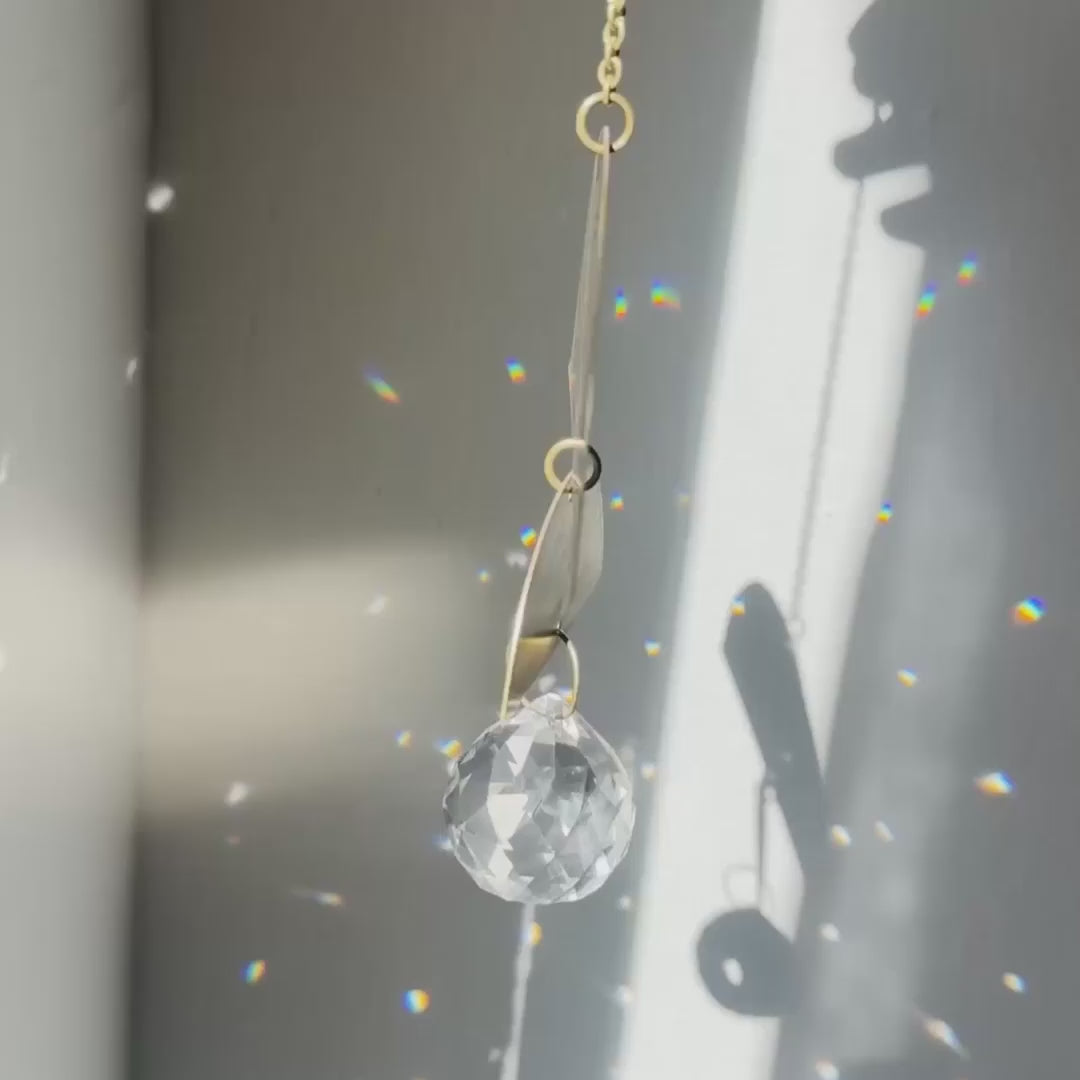 half moon shaped brass suncatcher with light reflections and rainbows