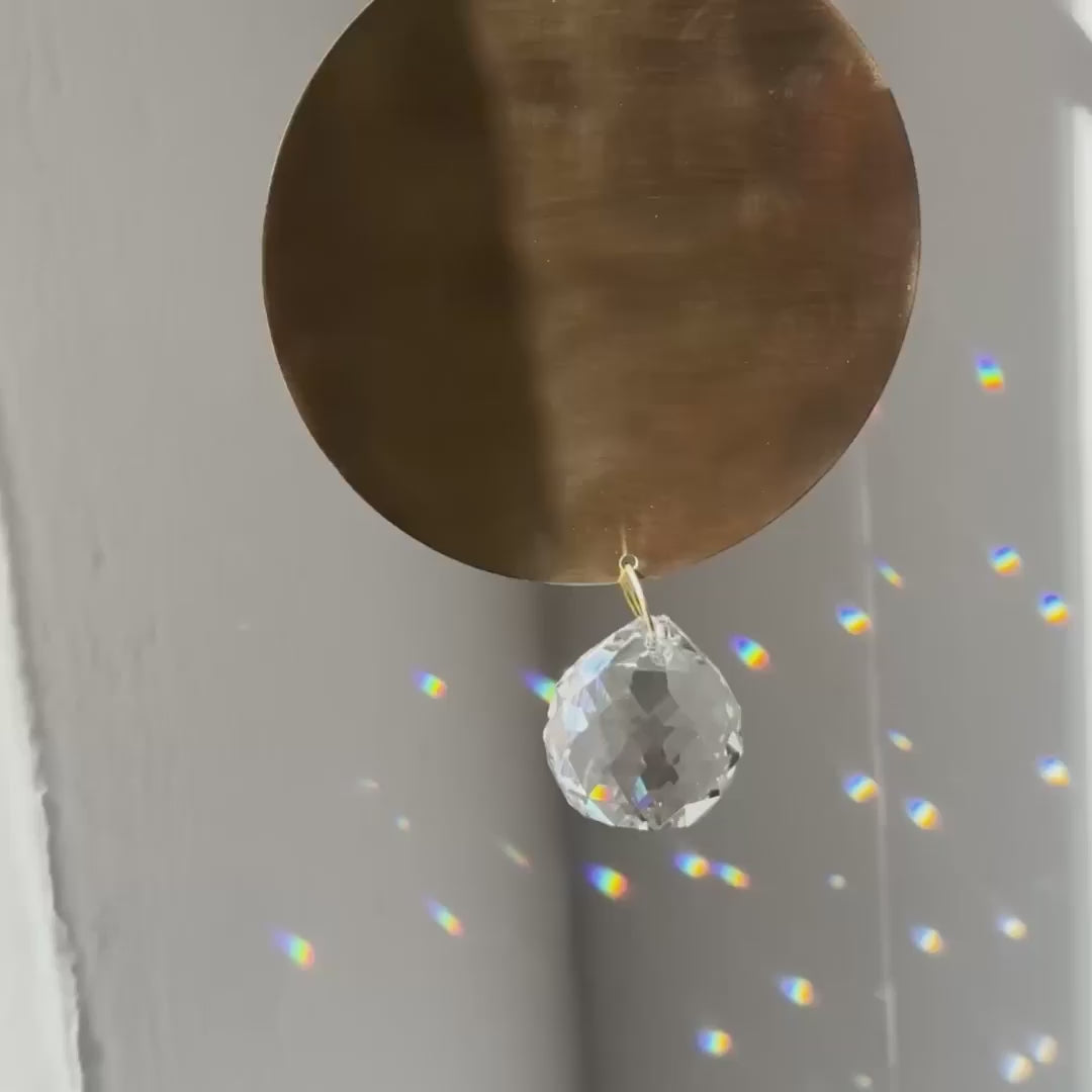 full moon shaped brass suncatcher with light reflections and rainbows