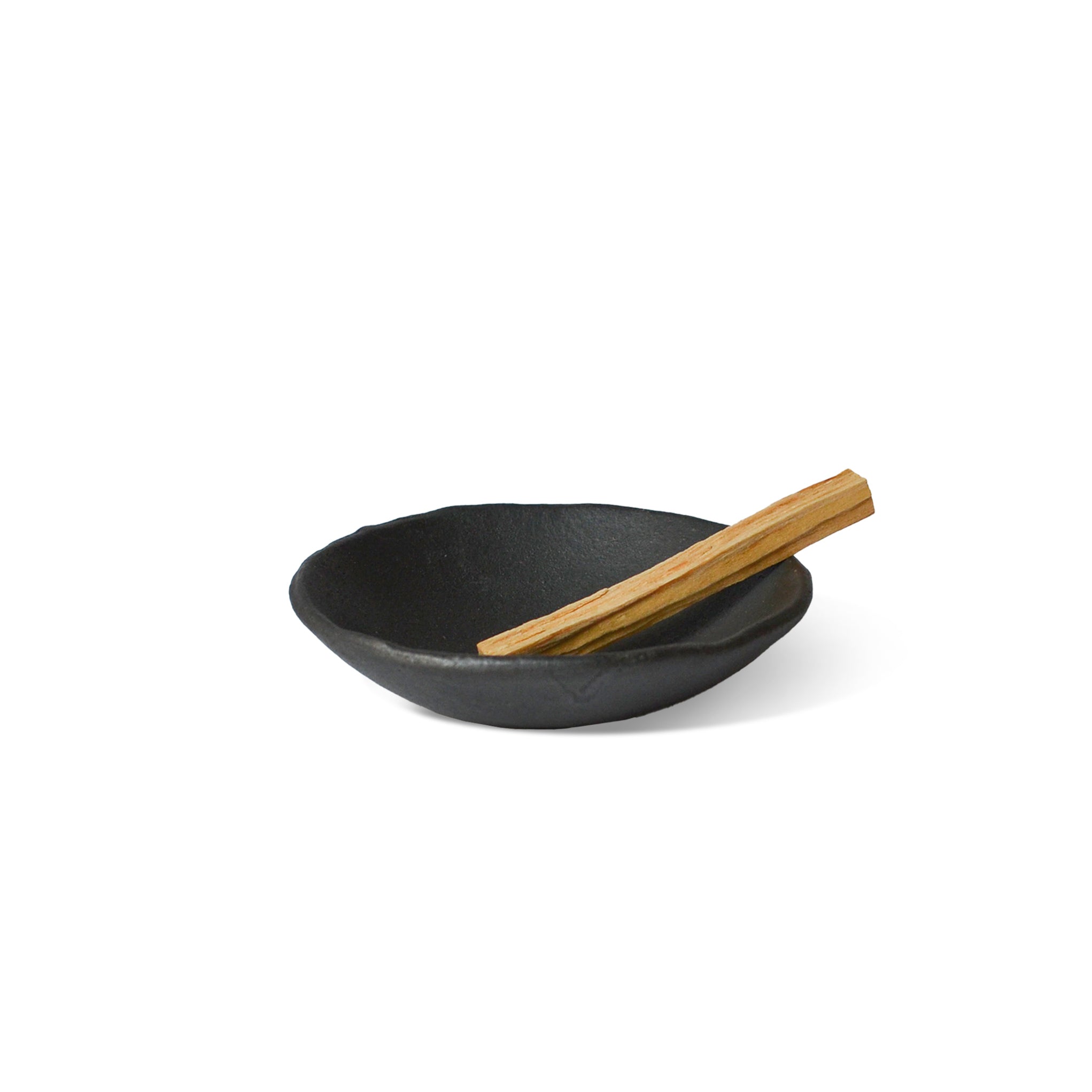 smudge stick on the raw black clay incense bowl