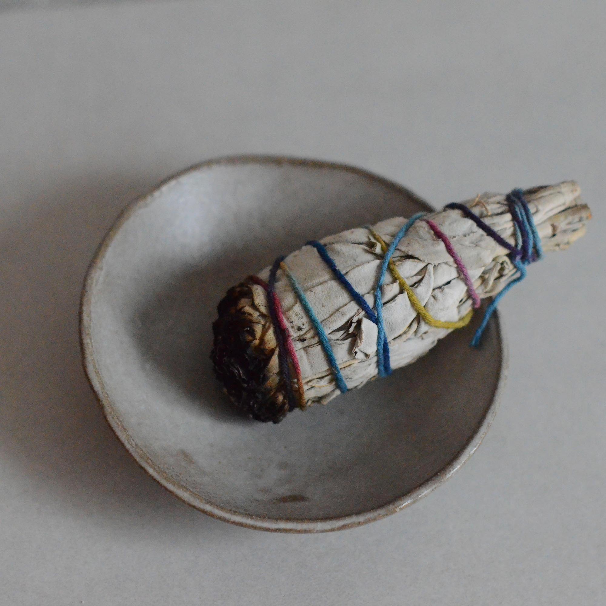 a smudge stick on the sand ceramic incense bowl