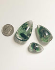 several drop shaped green ghost crystals with different size and quarter dollar coin