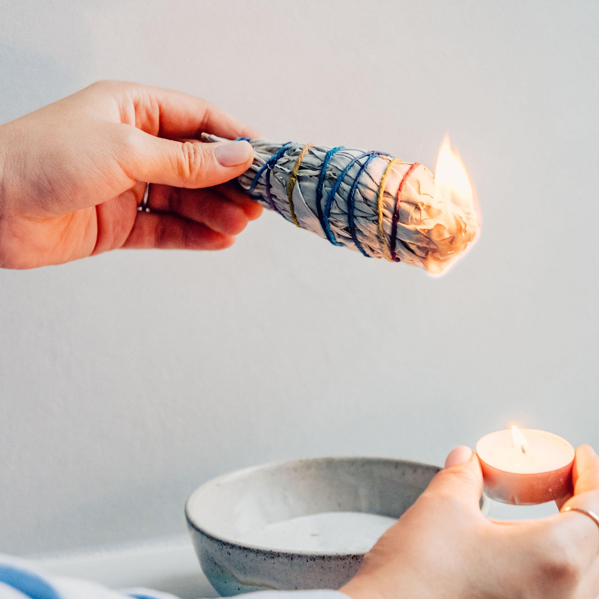 Left: Holding white sage smudge stick, Right: holding mini candle to lit the sage smudge stick.