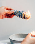 Left: Holding white sage smudge stick, Right: holding mini candle to lit the sage smudge stick.