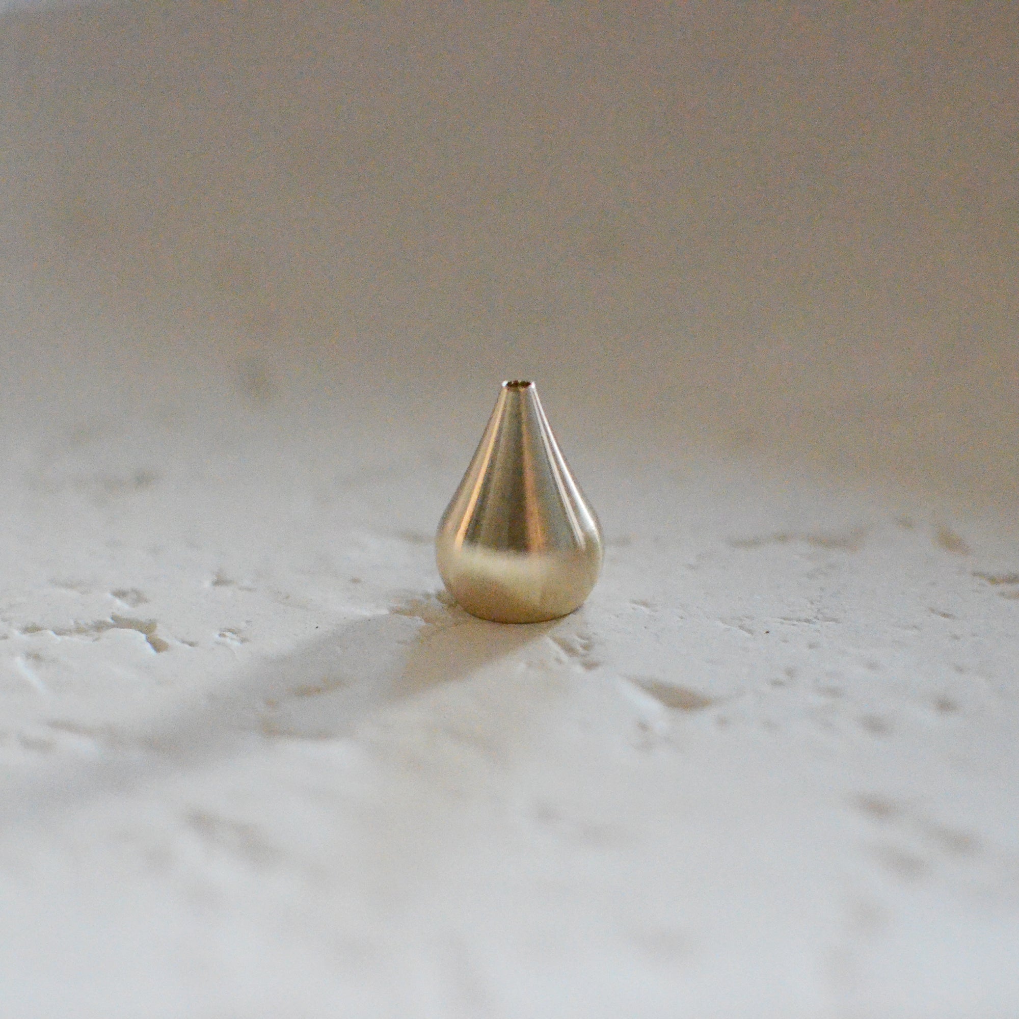 an incense holder made of brass and with a shape of tall waterdrop
