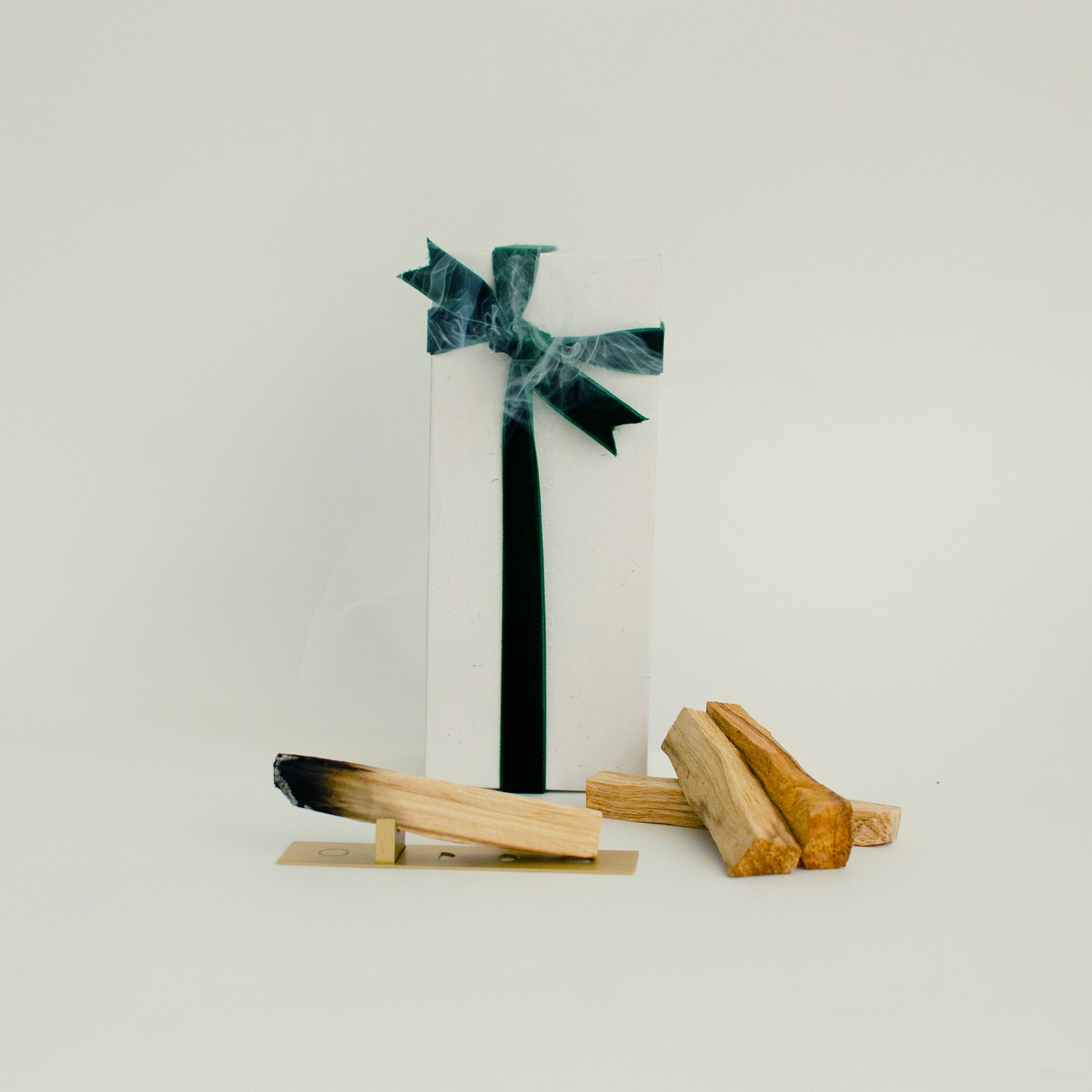 Palo Santo wood sticks with brass burner and white gift box tied with green velvet ribbon, releasing aromatic smoke — Cedar & Myrrh Warm Welcome Gift Set
