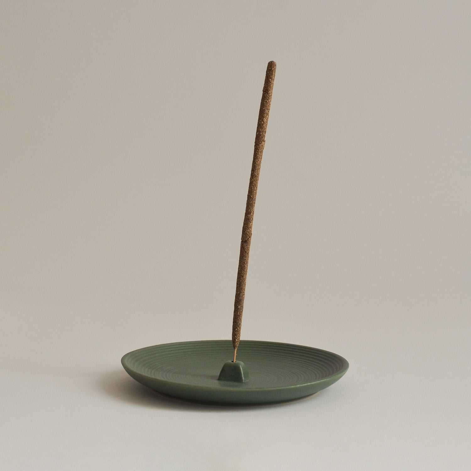 green wheel-thrown incense holder with incense stick