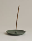 green wheel-thrown incense holder with incense stick